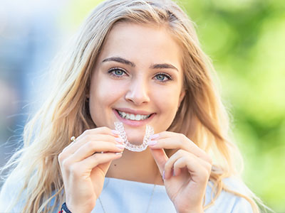 Smiling woman holding a toothbrush with a toothpaste logo, showcasing dental hygiene.